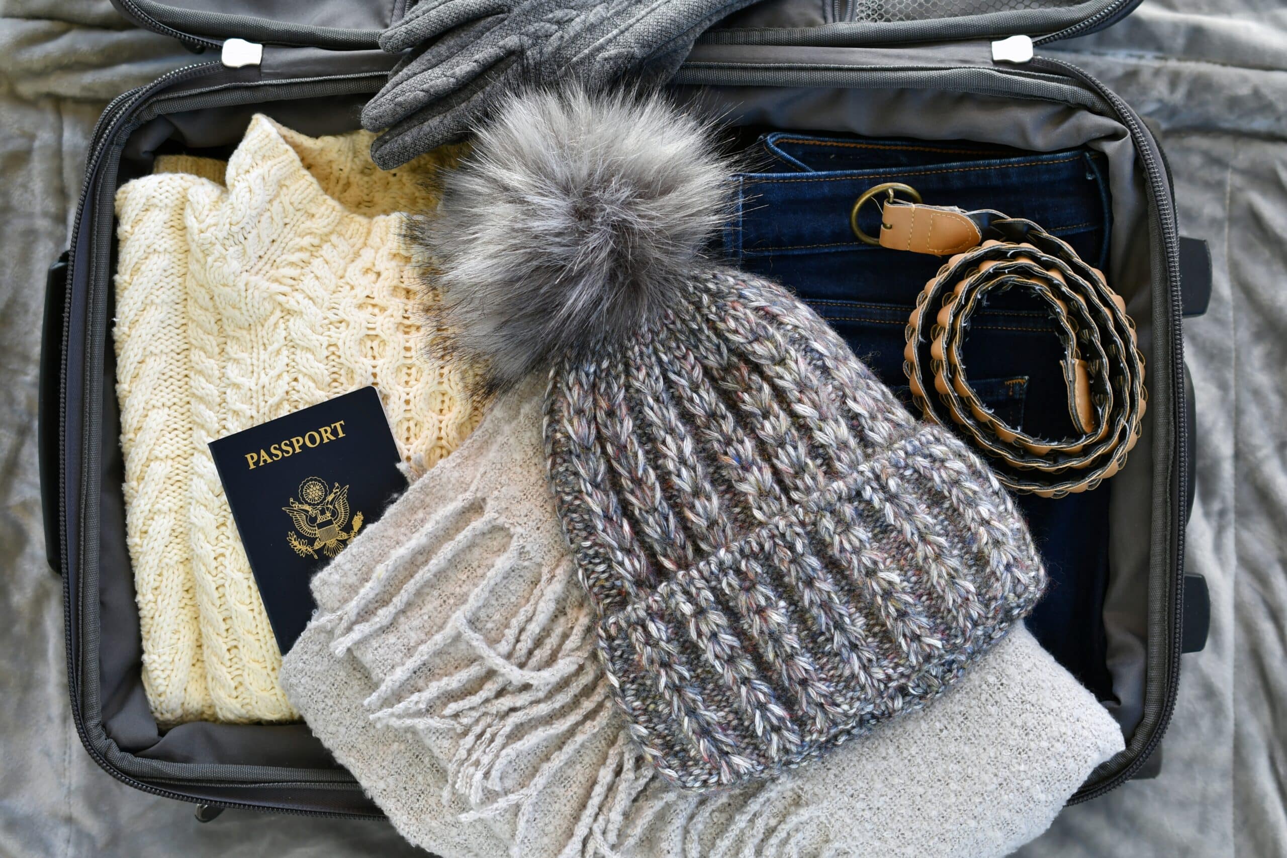 Packing winter clothes in an suitcase.
